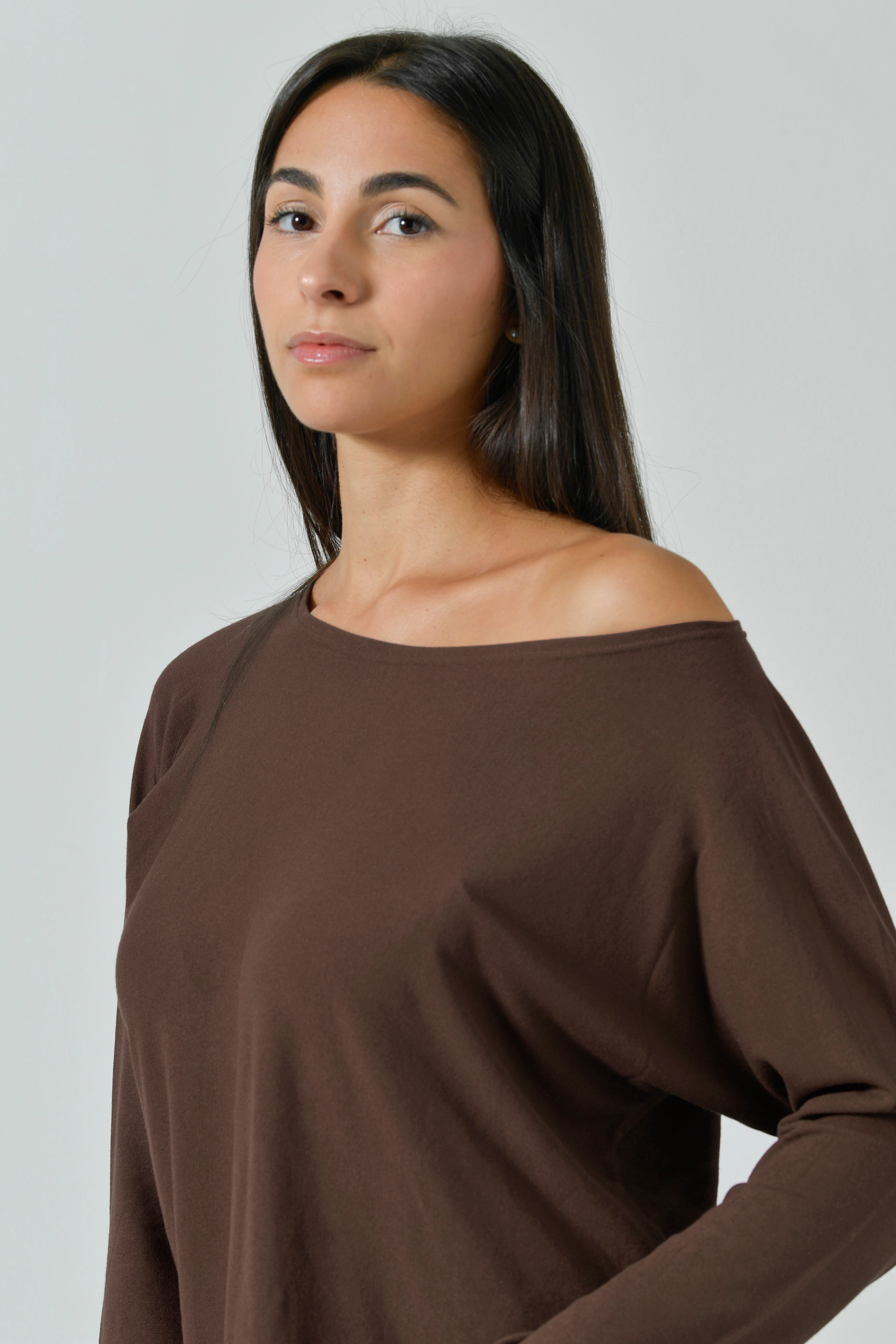Modella di tre quarti con la maglia color cocoa, scollo a barchetta scivolato sulla spalla